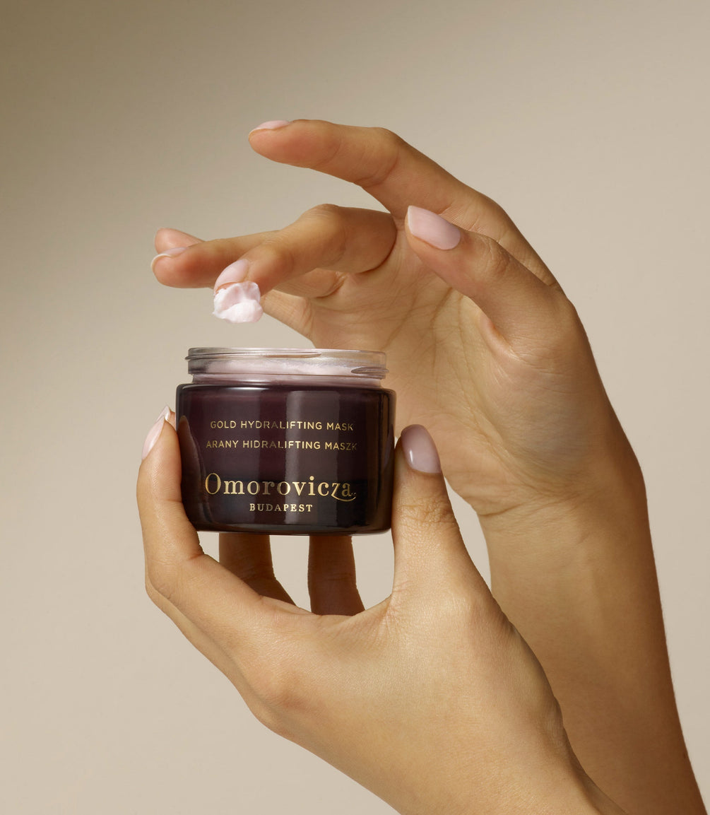 Hands are holding Gold Hydralifting Mask designed to provide an instant lift and deep hydration.