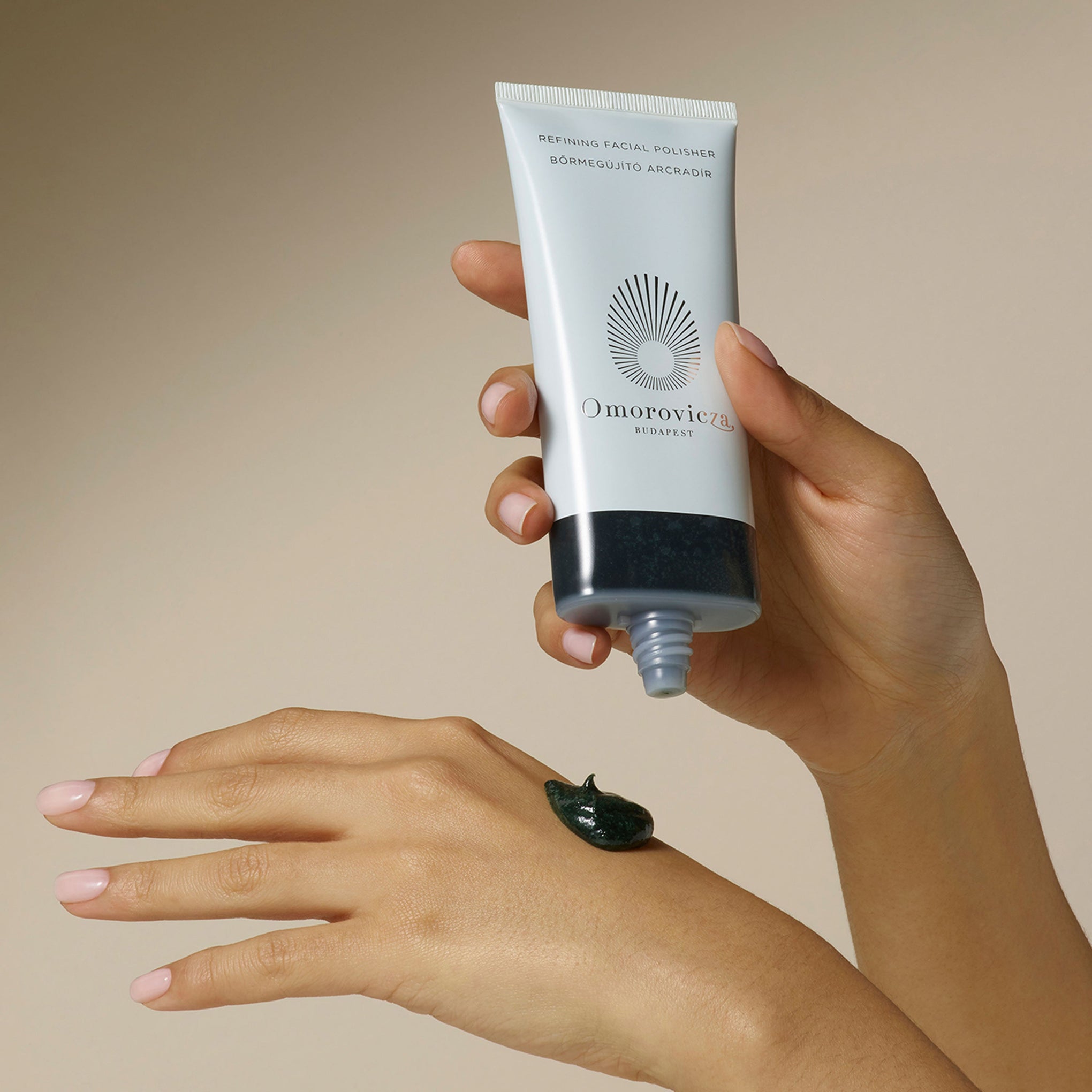 A close up of hands applying a pea size of Refining Facial Polisher.