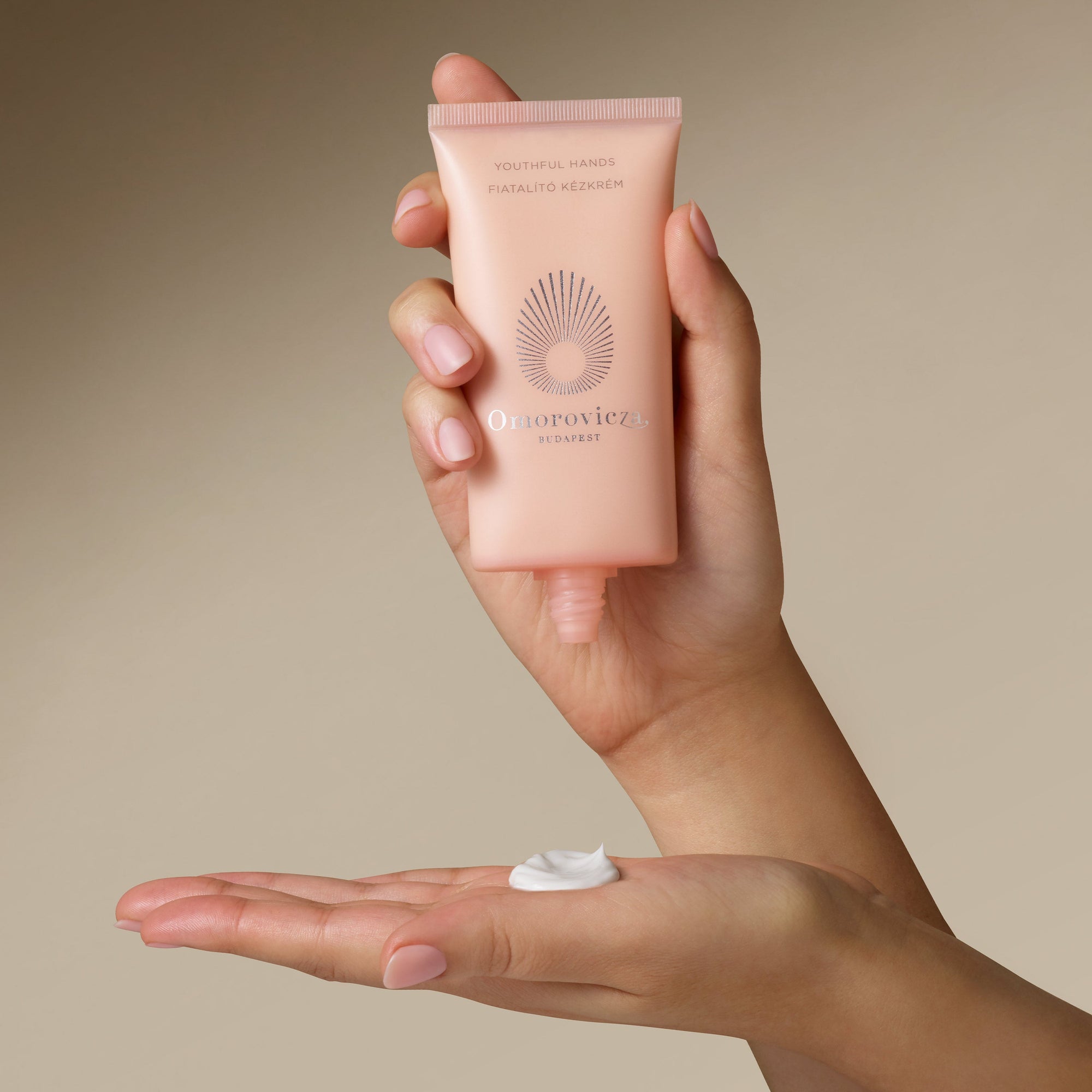 Hands are holding a tube of Youthful Hands cream.